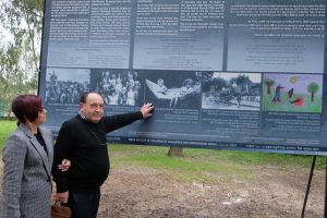 Elis Rutšteinas su žmona Loren prie Holokausto aukas menančio stendo Vilkaviškyje rodo savo brolio ir sesės nuotrauką (2017 m. rugsėjis) / asmeninio archyvo nuotr.