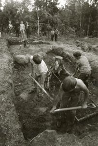 Zastaučių (Mažeikių raj.) I-IV a. pilkapių ir kapinyno archeologiniai kasinėjimai. Archeologas Vitas Valatka stovi keturių asmenų grupėje pirmas iš dešinės. 1974 m. rugpjūtis. Fotografas Bronius Gadeikis