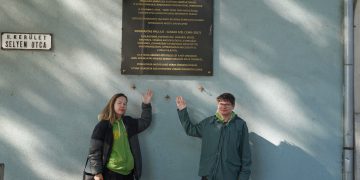 Aistė ir Augustinas prie atminimo lentos Pauliui Normantui Vengrijoje